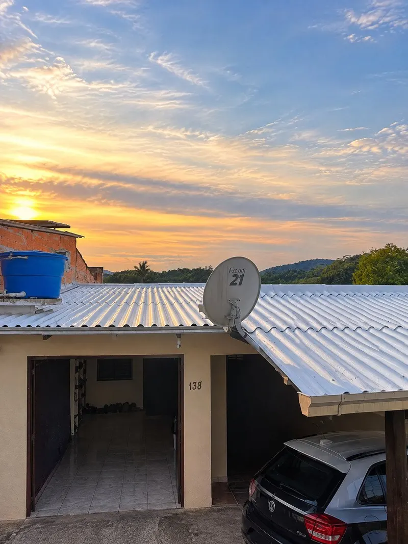 Cobertura residencial com telhas tratadas, garagem e horizonte de morros