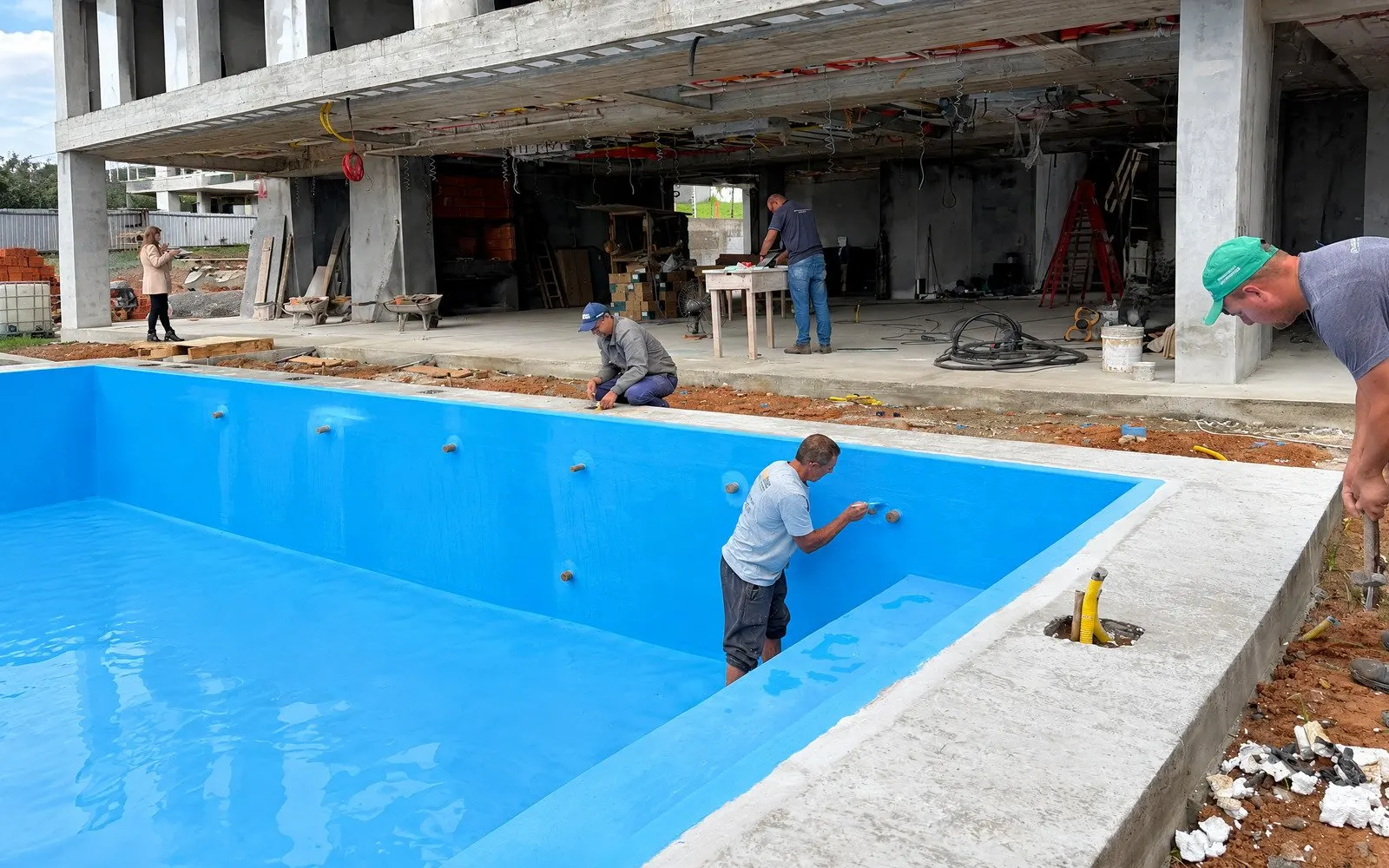 Equipe ImperMais aplicando membrana impermeabilizante em piscina de concreto em obra