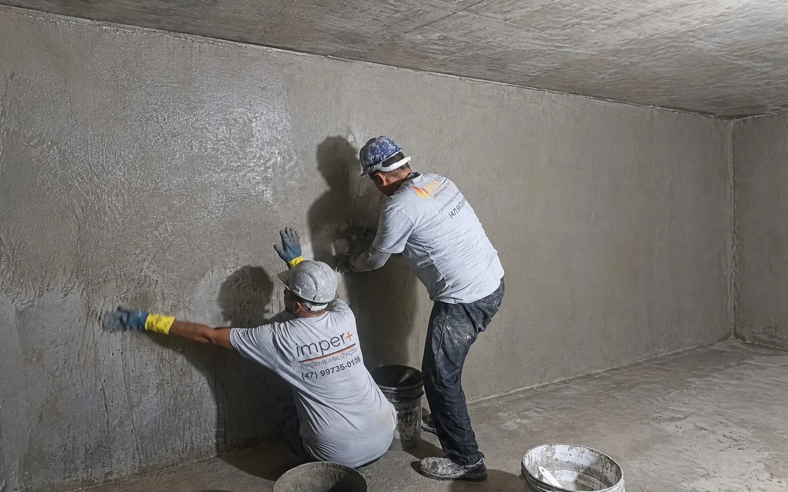 Equipe ImperMais aplicando impermeabilizante no interior de reservatório de concreto