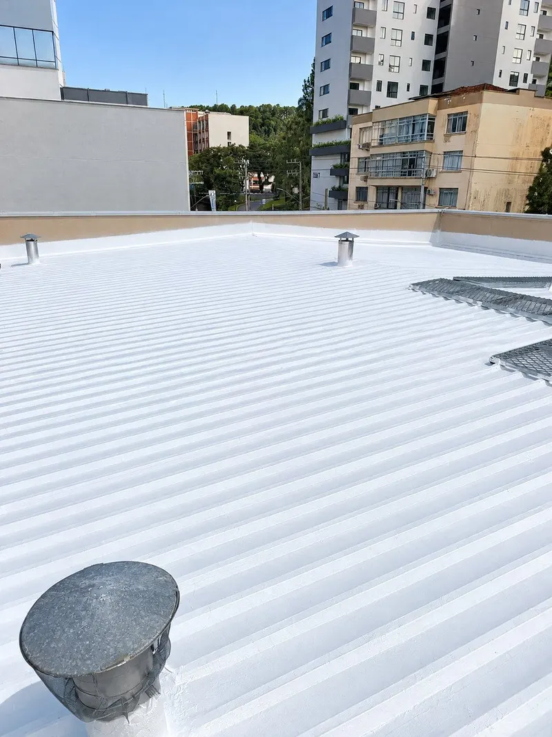 Cobertura plana com membrana branca contínua, exaustores e arremates perimetrais